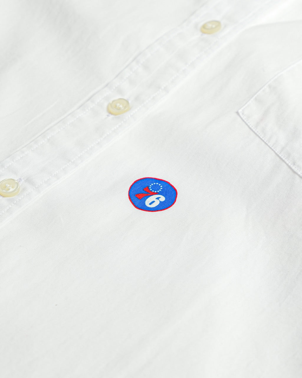 Close-up of white Sports Oxford shirt with 76ers logo and button details
