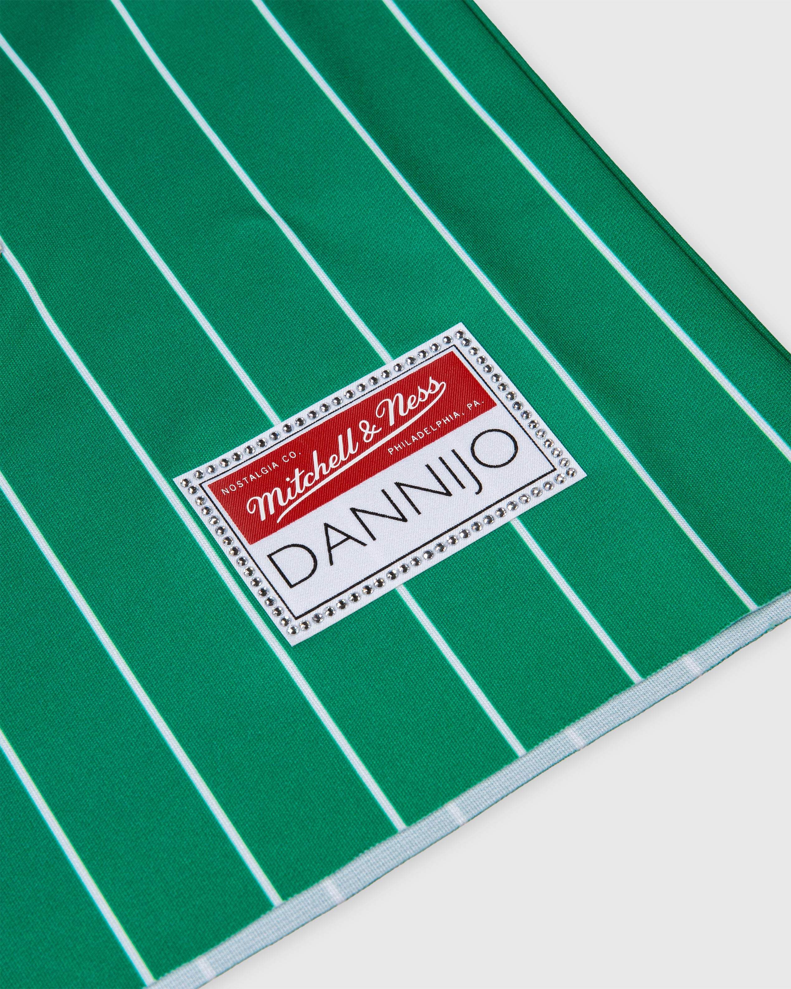 Green and white striped fabric with Mitchell & Ness label on Larry Bird Boston Celtics rhinestone crop football jersey