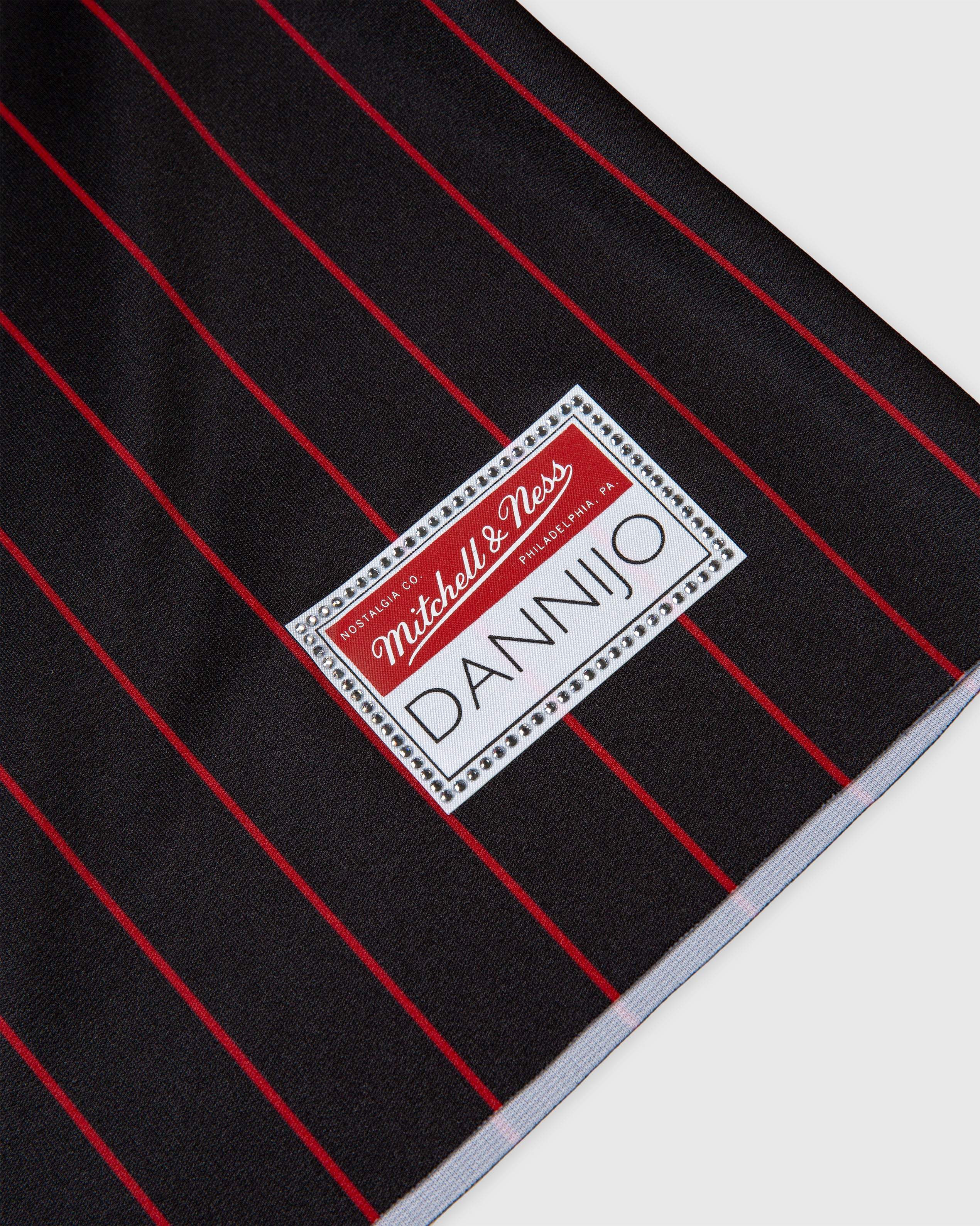 Black and red striped fabric with Mitchell & Ness and DANNIJO labels, part of Dwyane Wade Miami Heat rhinestone crop football jersey collection