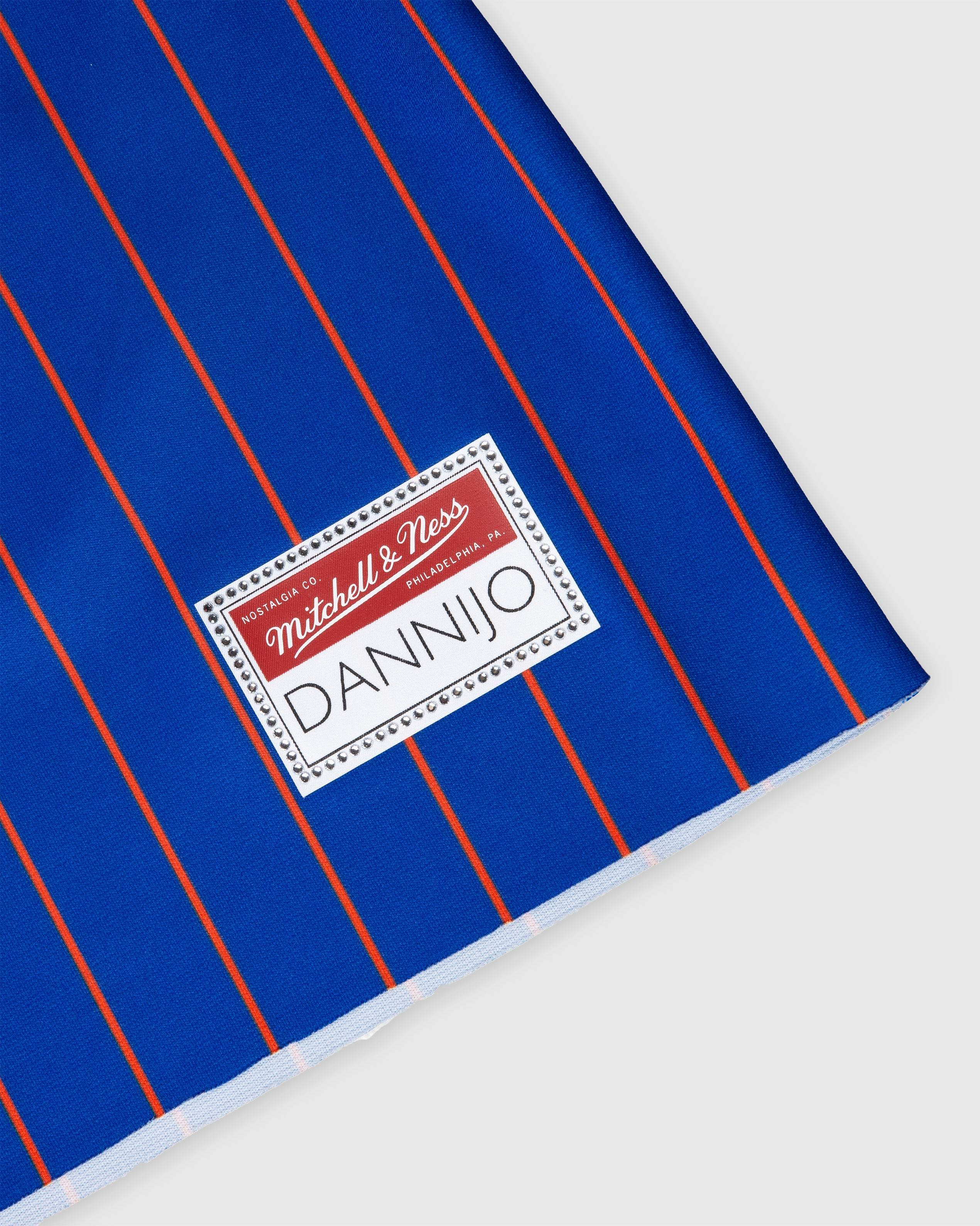 Close-up of Mitchell & Ness patch on blue and orange striped Patrick Ewing New York Knicks rhinestone crop football jersey